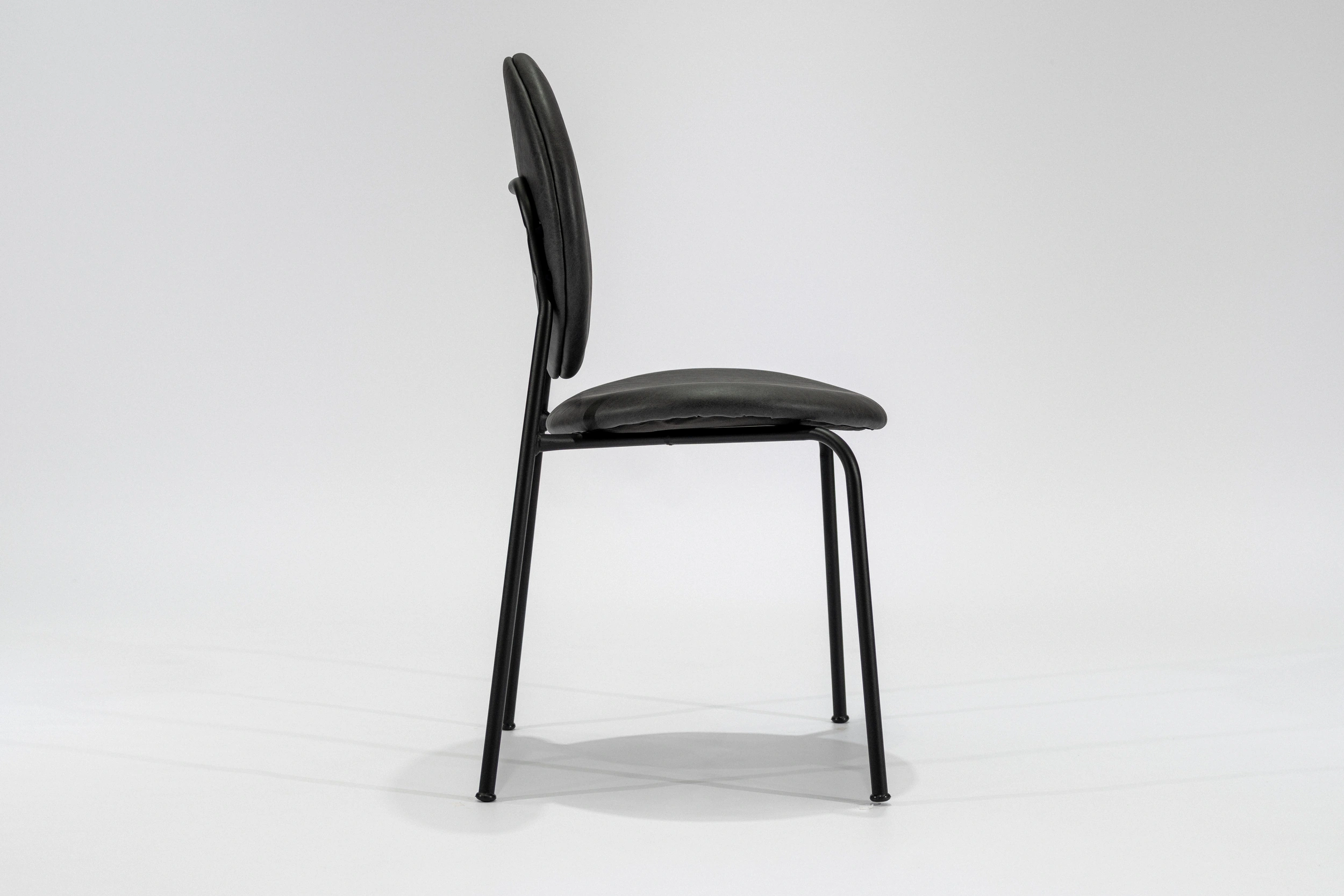 silla-comedor-tapizada-simil-cuero-gris-oscuro-hierro-negro-lateral. Silla de comedor tapizada en ecocuero color gris oscuro con estructura de hierro negro microtexturado vista lateral