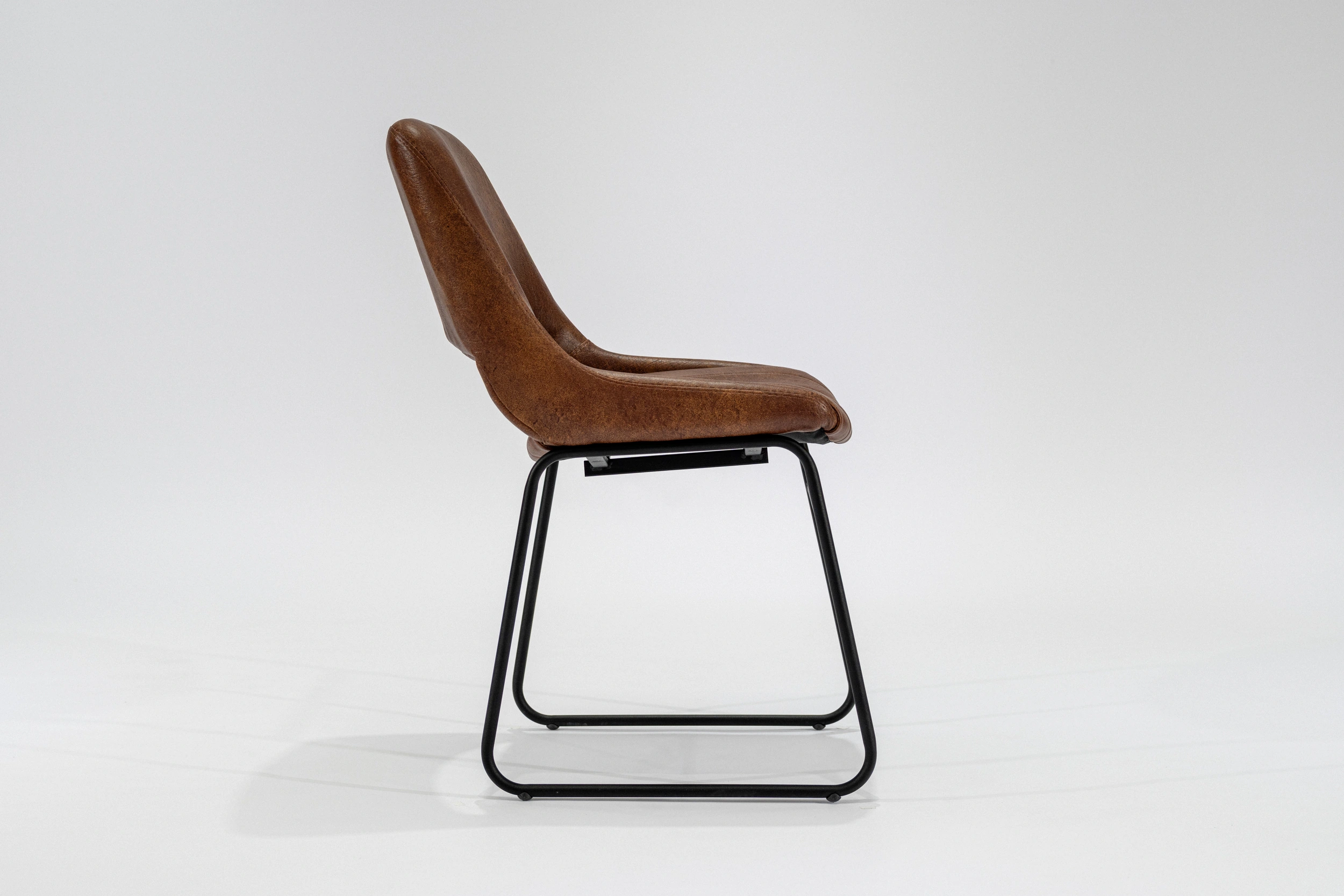 silla-comedor-tapizada-simil-cuero-habano-hierro-negro-lateral... Silla de comedor tapizada en ecocuero color habano con estructura de hierro negro microtexturado vista lateral