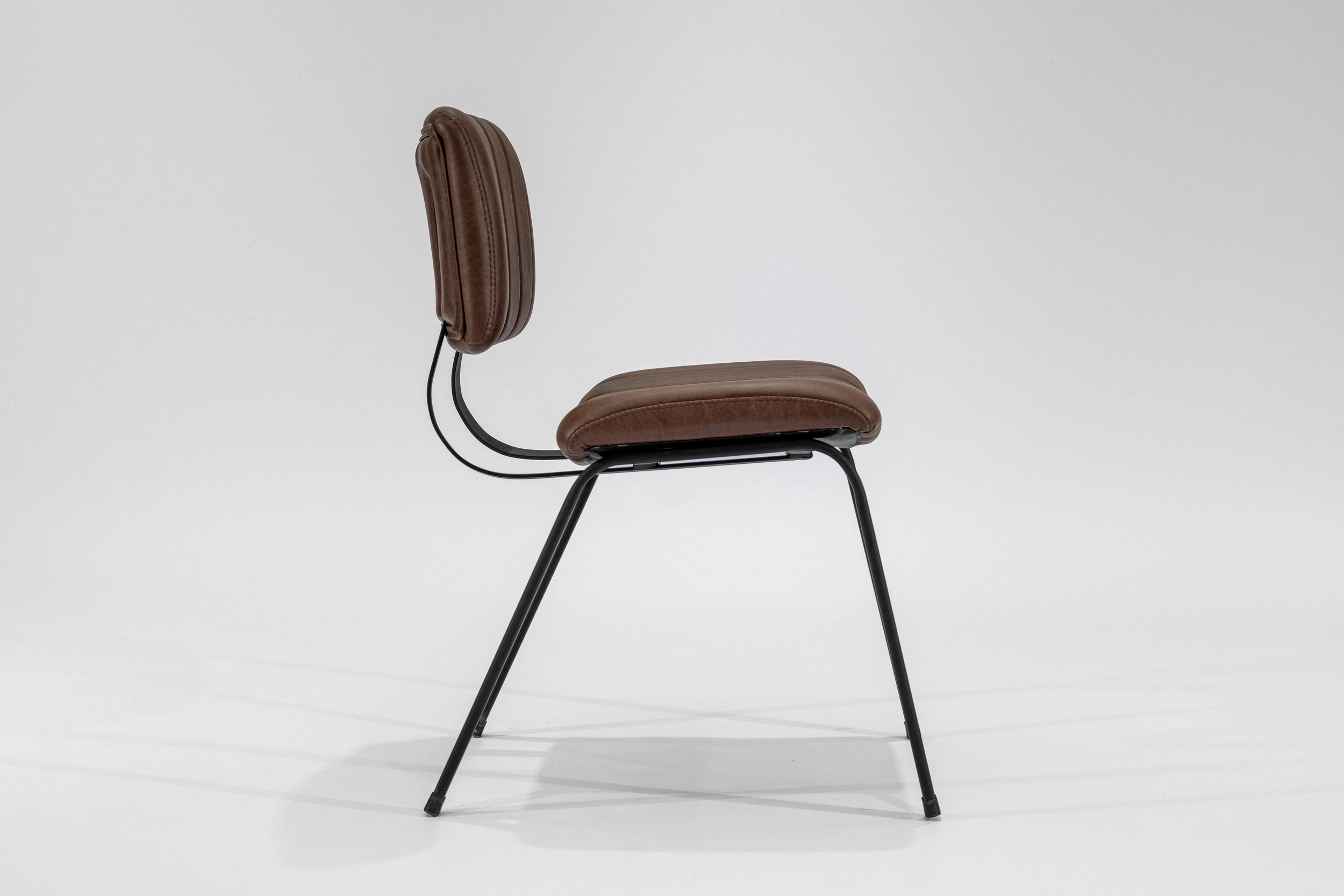 silla-comedor-tapizada-simil-cuero-habano-hierro-negro-lateral.. Silla de comedor tapizada en ecocuero color habano con estructura de hierro negro microtexturado vista lateral