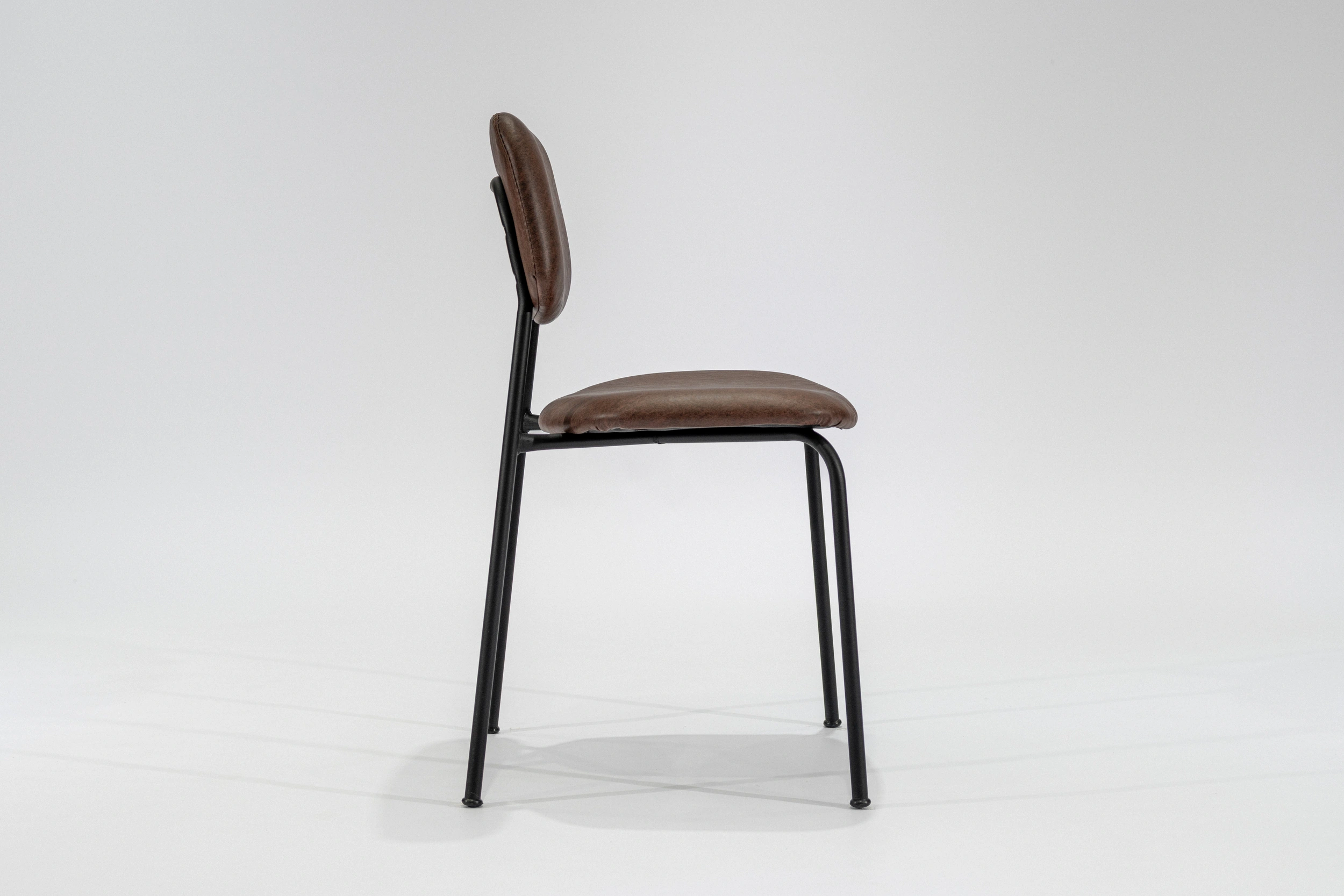 silla-comedor-tapizada-simil-cuero-habano-hierro-negro-lateral. Silla de comedor tapizada en ecocuero color habano con estructura de hierro negro microtexturado vista lateral