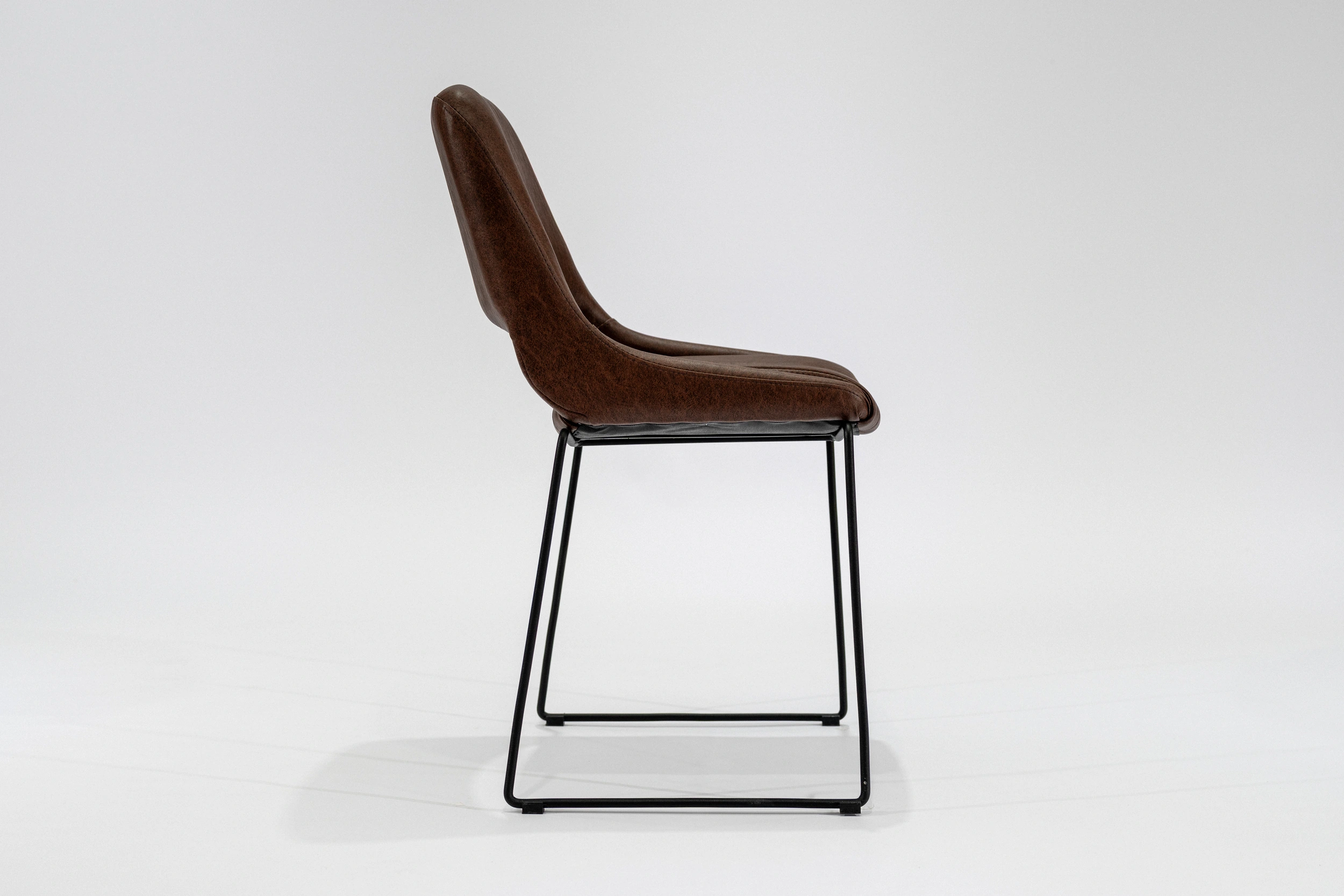 silla-comedor-tapizada-simil-cuero-habano-hierro-negro-lateral.... Silla de comedor tapizada en ecocuero color habano con estructura de hierro negro microtexturado vista lateral