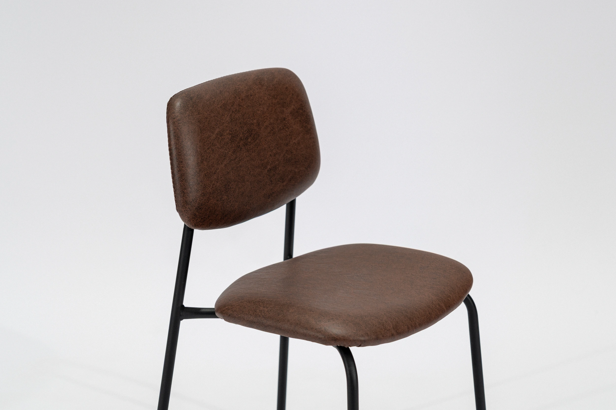 silla-comedor-tapizada-simil-cuero-habano-hierro-negro-perspectiva. Silla de comedor tapizada en ecocuero color habano con estructura de hierro negro microtexturado vista perspectiva