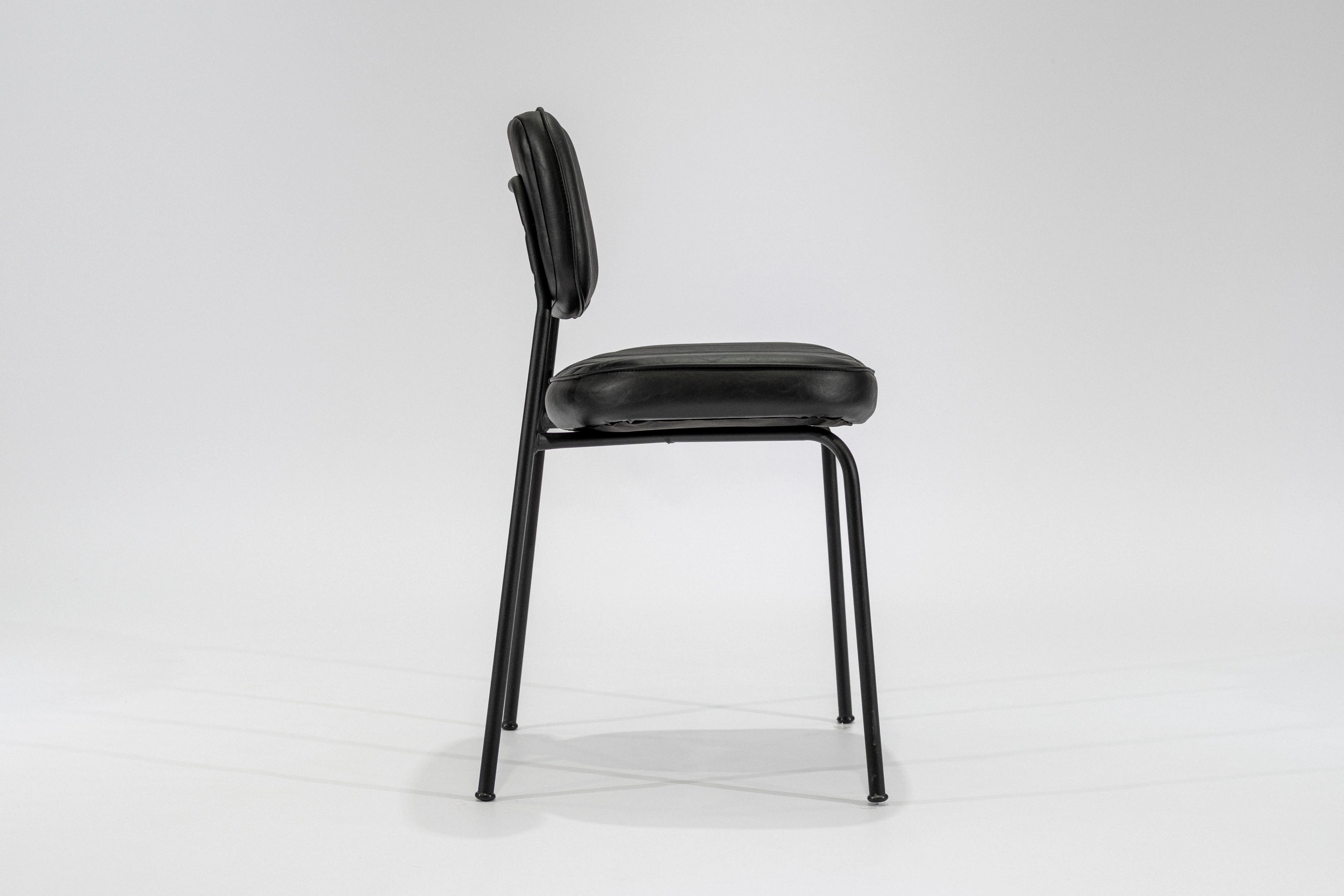 silla-comedor-tapizada-simil-cuero-negro-hierro-negro-lateral.. Silla de comedor tapizada en ecocuero color negro con estructura de hierro negro microtexturado vista lateral