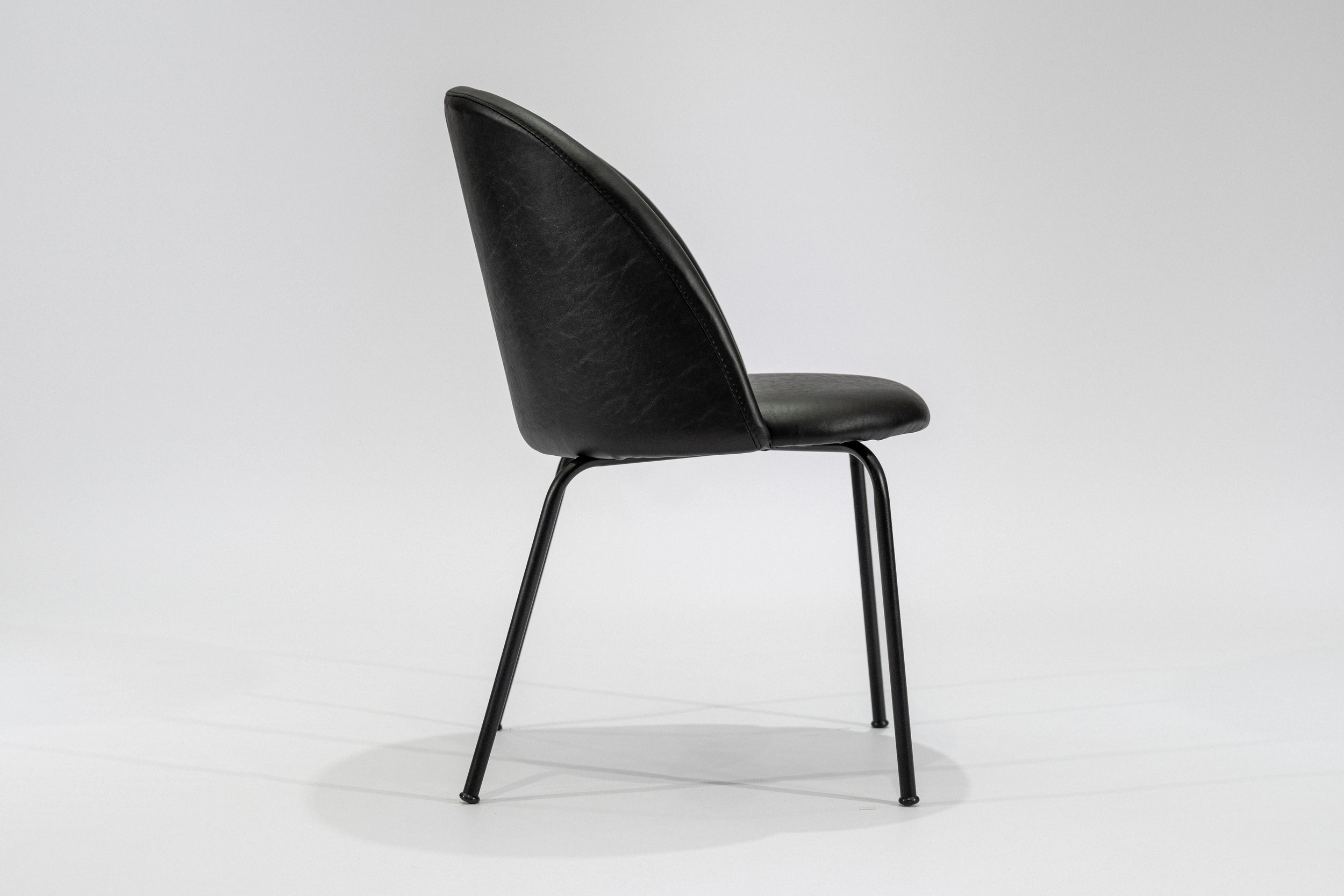 silla-comedor-tapizada-simil-cuero-negro-hierro-negro-lateral.... Silla de comedor tapizada en ecocuero color negro con estructura de hierro negro microtexturado vista lateral