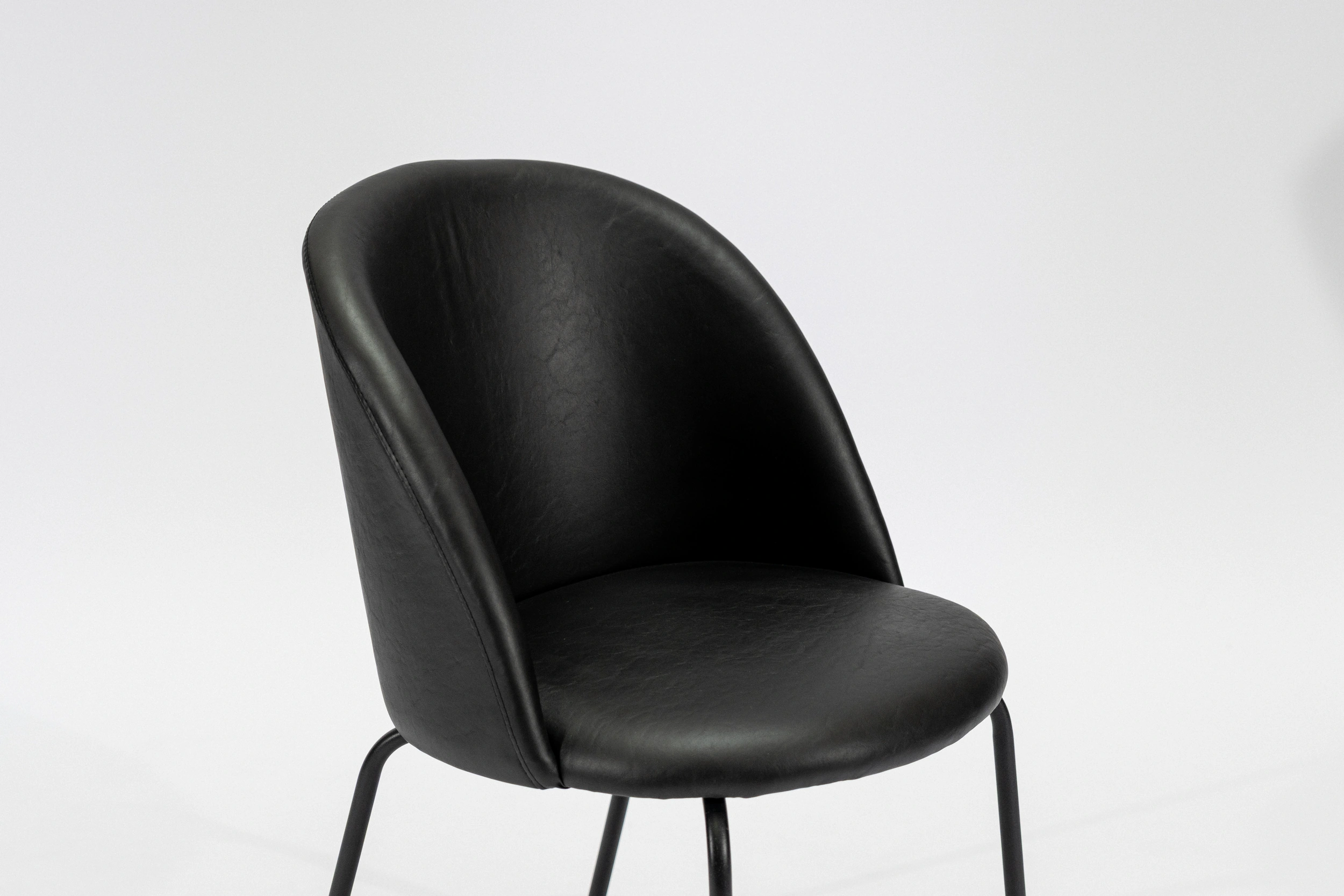 silla-comedor-tapizada-simil-cuero-negro-hierro-negro-perspectiva.... Silla de comedor tapizada en ecocuero color negro con estructura de hierro negro microtexturado vista perspectiva