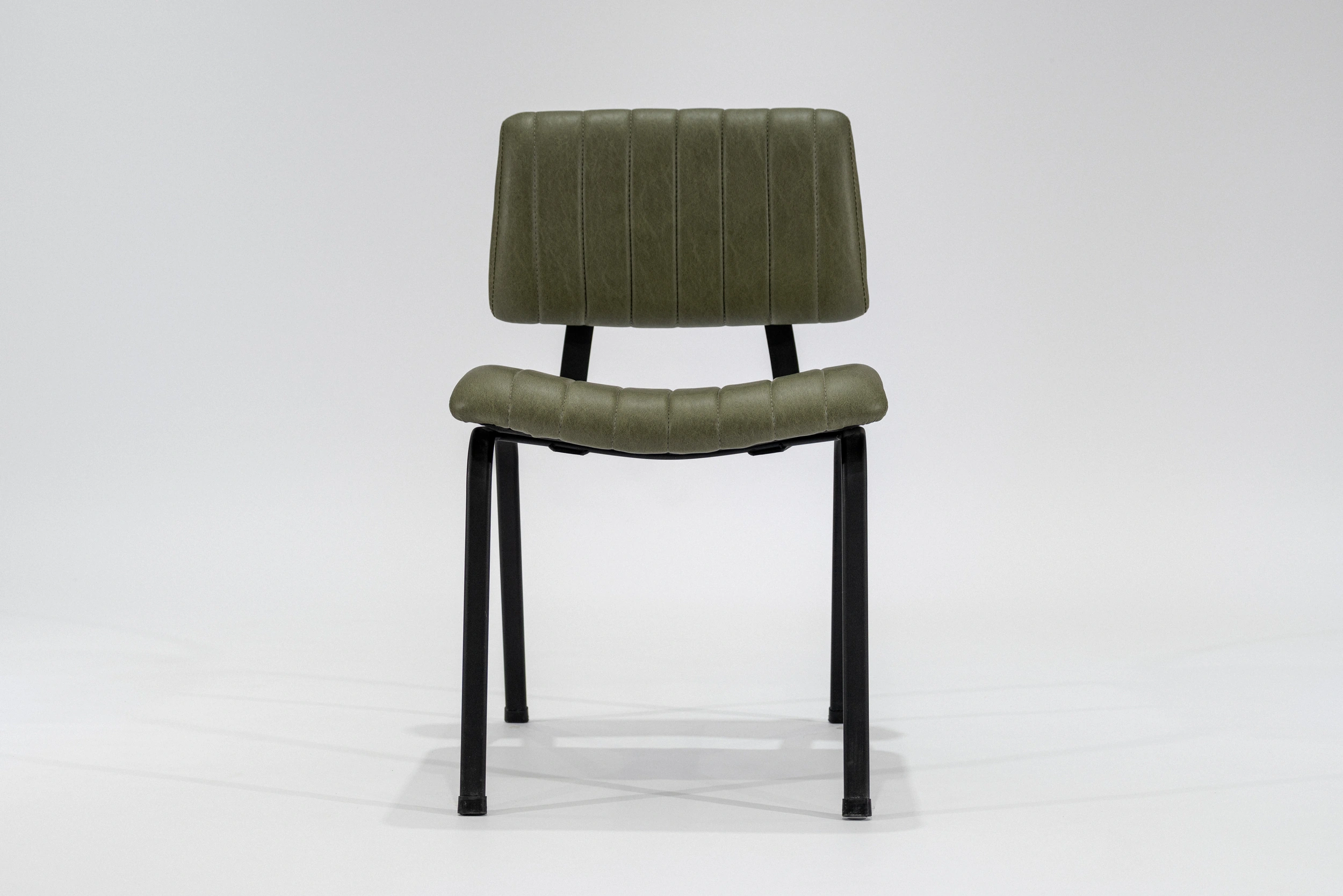 silla-comedor-tapizada-simil-cuero-verde-seco-hierro-negro-frontal Silla de comedor tapizada en ecocuero color verde seco con estructura de hierro negro microtexturado vista frontal.