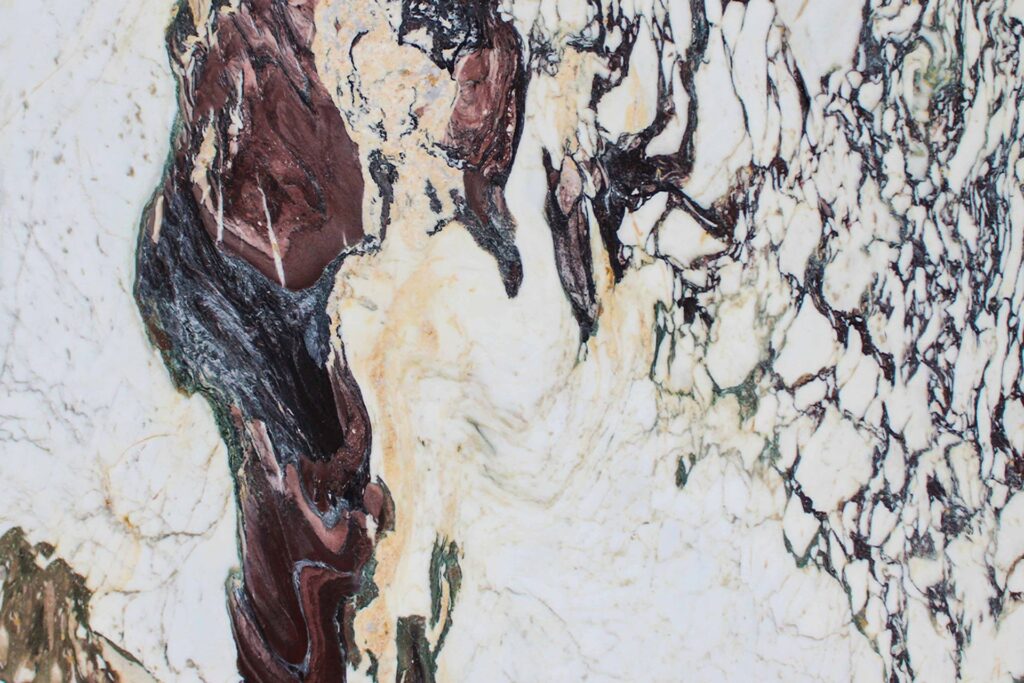 Mármol Calacatta Monet natural con fondo blanco y expresivas vetas bordó, negras y doradas, ideal para mesadas de baño, revestimientos y proyectos de interiorismo.