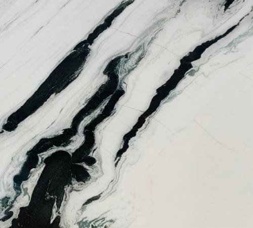 marmol-dalmata Mármol Dálmata natural de fondo blanco con vetas negras y grises, ideal para revestimientos, mesadas de baño, mesadas de vanitory y proyectos de interiorismo de alta gama.