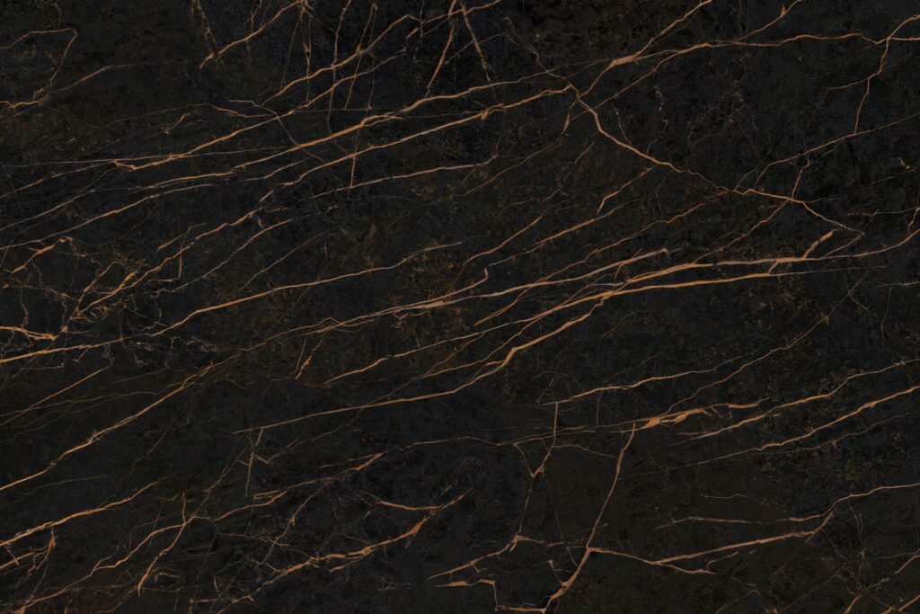 Neolith Mamba, piedra sinterizada de fondo negro profundo con finas vetas doradas y cobrizas, ideal para mesadas y revestimientos.